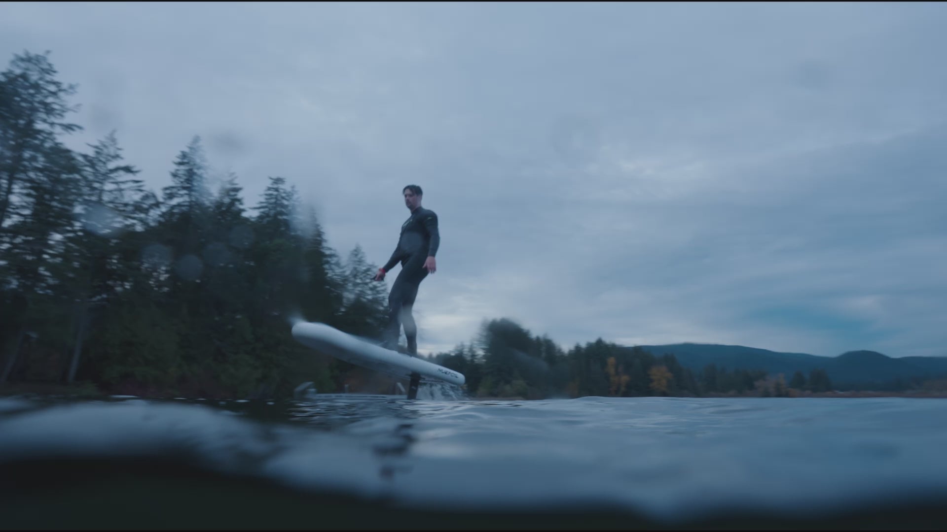 A person carving loops in the water while riding an eFoil board, creating dynamic curves on the surface.